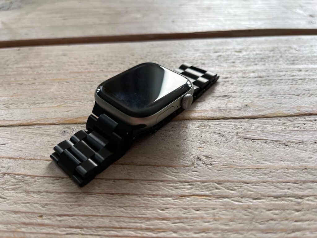 Zwarte roestvrij stalen schakelband van 123watches bevestigd op een Apple Watch op een houten ondergrond